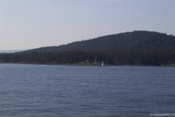 Lighthouse and sail boat in the distance  in the Swartz Bay in Canada as viewed from ferry to Victoria.jpg